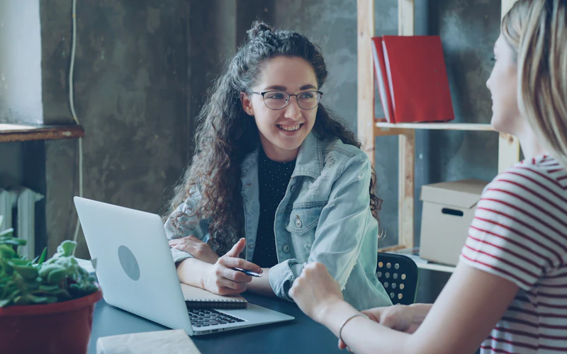 Two people talking through a project at a laptop