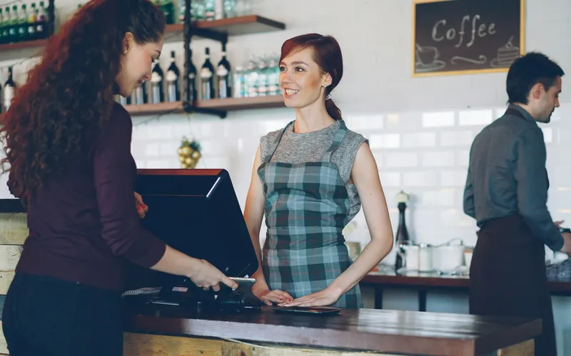A customer paying by card at a cafe counter